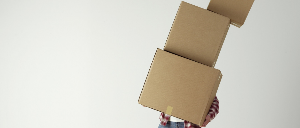 Man lifting 3 boxes and slanting sideways, technology for charities can help do the heavy lifting