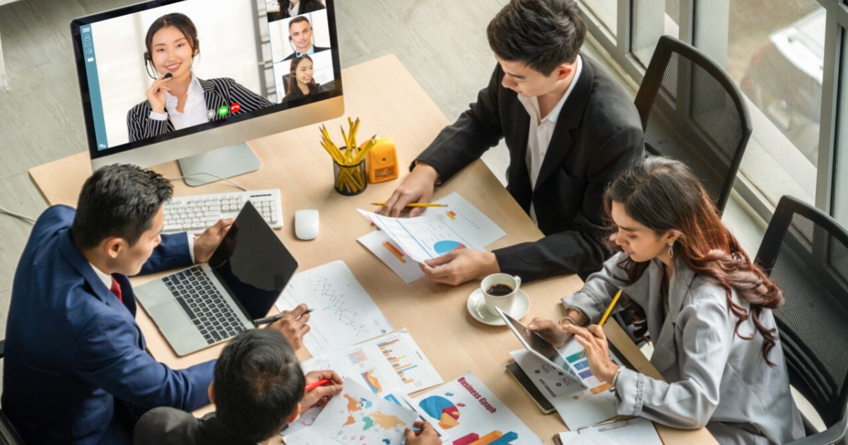 conference meeting with 4 people at a table and one presenter on a monitor