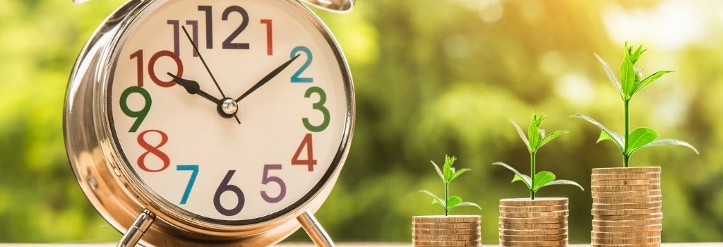 alarm clock and growing plants on top of stacked coins